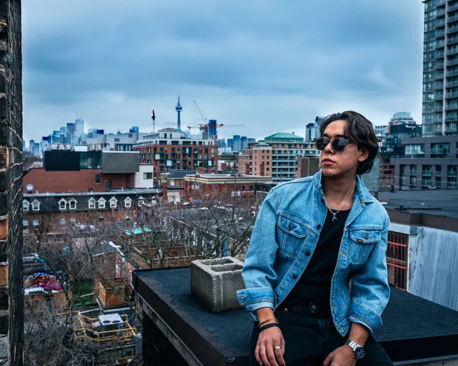 Zeegwon Shilling on a Toronto rooftop with the city skyline behind him